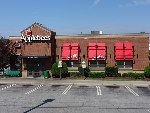 An Applebee's restaurant with sign and three red windows to right.