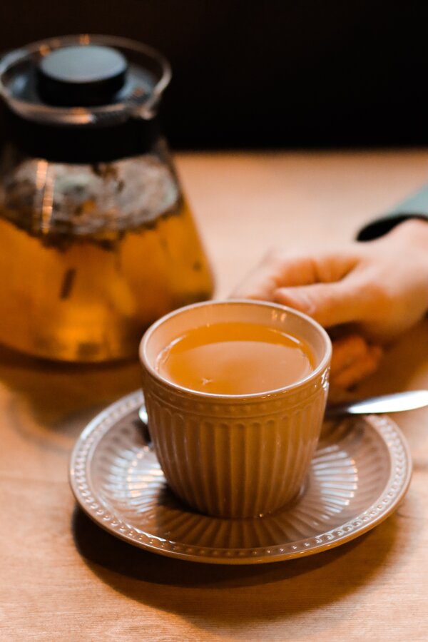 Teapot, cup of tea and hands