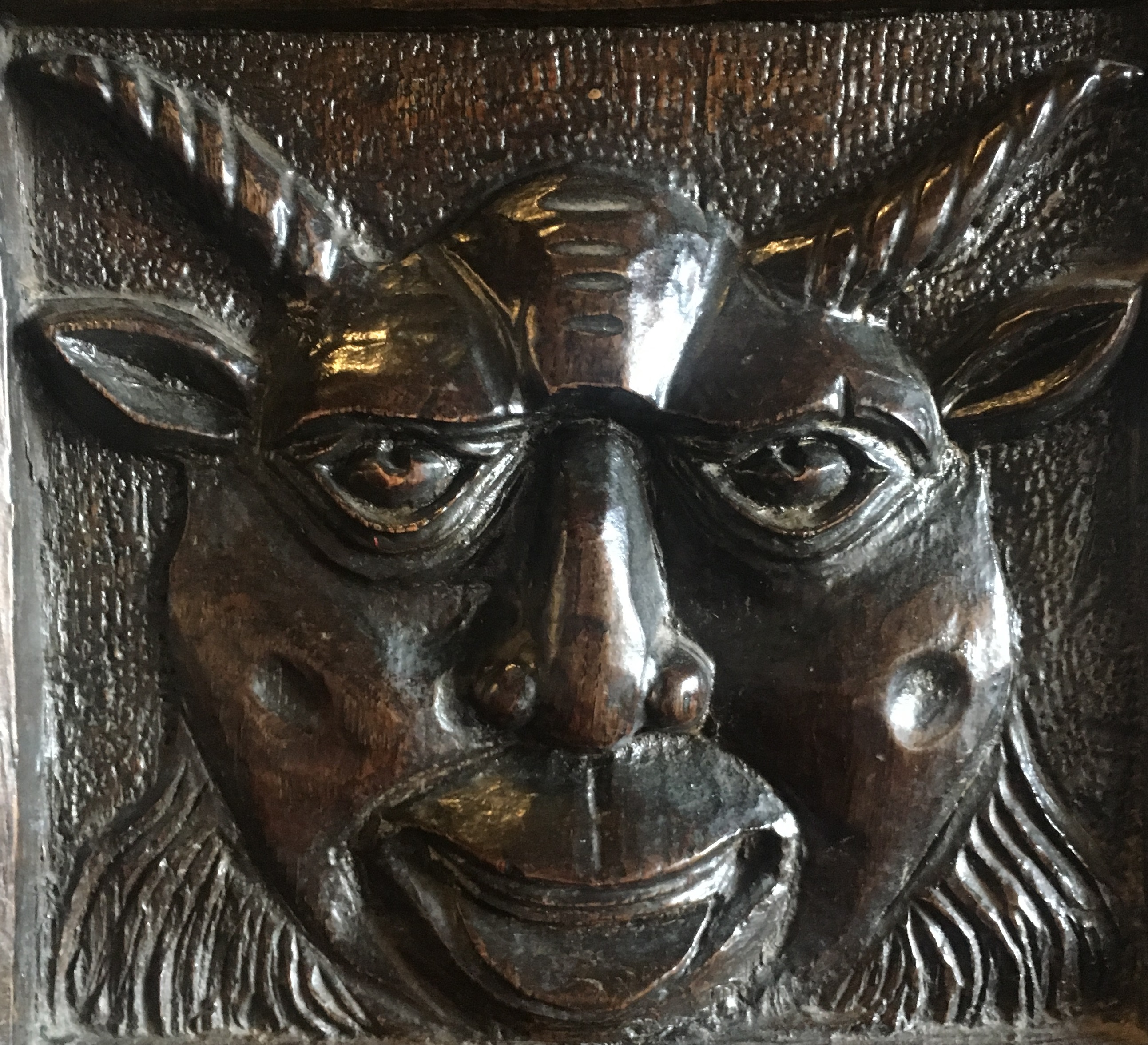 Grotesque carved wooden face with horns