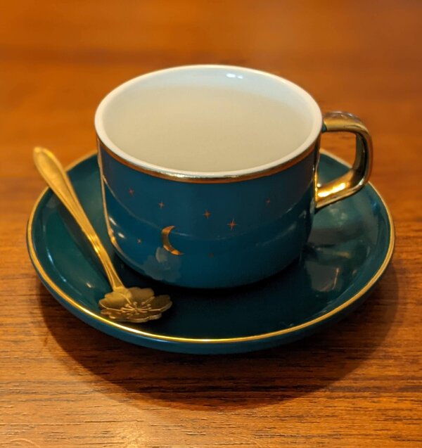 Photo (c) Alexandra Baez Blue mug with elaorate spoon to left and gold crescent moon and stars